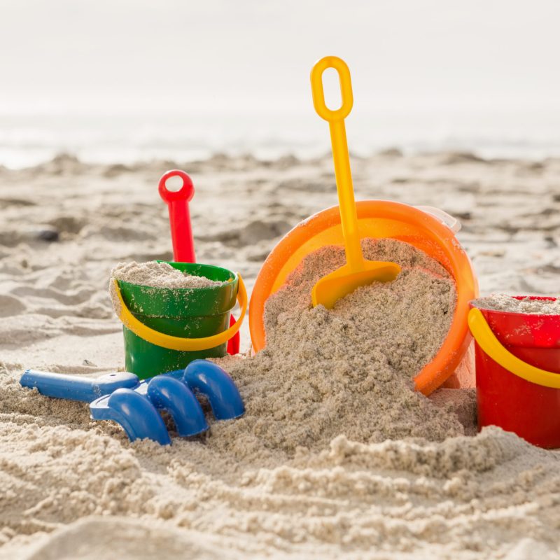 Three bucket with sand and a spade on tropical sand beach